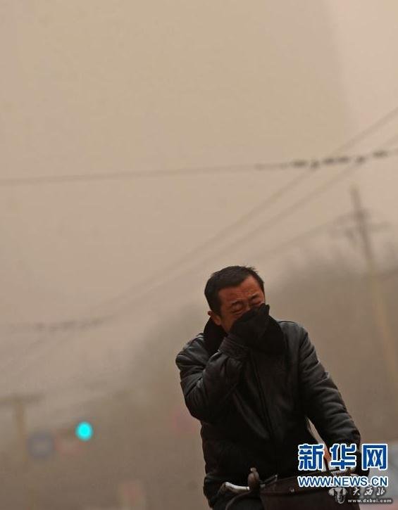 2月28日，在太原街頭，一位騎車人在沙塵暴中捂嘴前行。新華社記者范敏達 攝