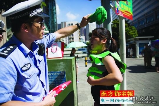  昨日，羅湖區(qū)一十字路口一女子闖紅燈被抓，很配合地穿上綠馬甲戴上綠帽子。南都記者 陳文才 攝