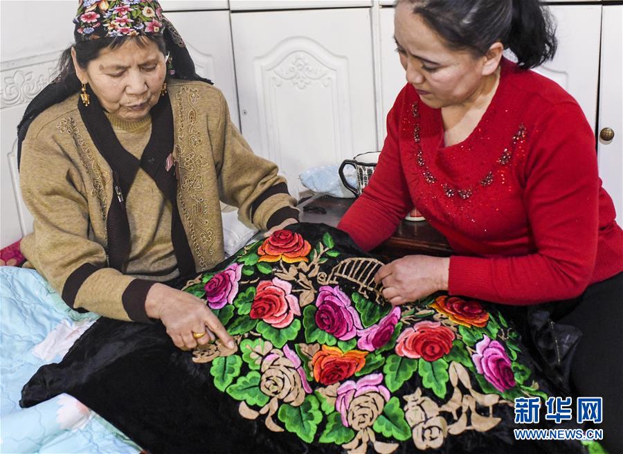 在新疆哈密市，刺繡藝人阿加汗·賽買提（左）和女兒探討針法（2019年3月6日攝）。